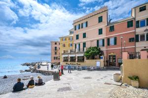 grupa ludzi siedzących na chodniku obok oceanu w obiekcie Casa Iole a Boccadasse - Genovainrelax w Genui