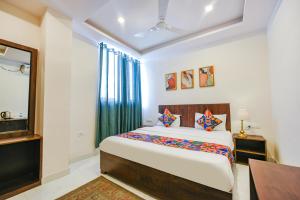 1 dormitorio con cama, escritorio y espejo en FabHotel Jaswinder Bhawan en Haridwār