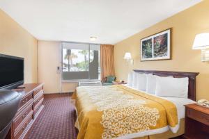 a hotel room with a bed and a flat screen tv at Howard Johnson by Wyndham Orlando-International Drive in Orlando