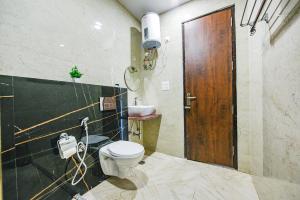 baño con aseo y puerta de madera en FabHotel Jaswinder Bhawan en Haridwār