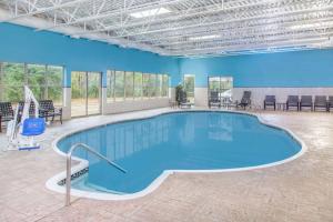 uma grande piscina numa sala com cadeiras e mesas em Hawthorn Suites Bloomington em Bloomington