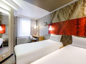 a hotel room with two beds and a desk at ibis Hotel München City in Munich