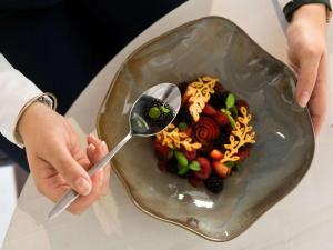 a person holding two spoons and a plate of food at Mercure Montpellier Centre Comédie in Montpellier