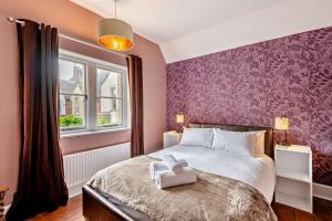 een slaapkamer met een bed en een paarse muur bij Old School Cottage in Sandgate