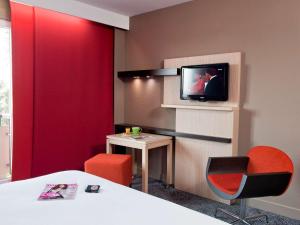 een kamer met een tv en een tafel en stoelen bij ibis Styles Saint Dizier in Saint-Dizier