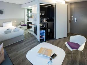 a room with a bed and a table with a laptop at Novotel Suites Luxembourg in Luxembourg