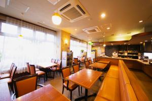 um restaurante com mesas e cadeiras de madeira e um bar em ホテルパブリック21 em Yokkaichi