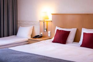 pokój hotelowy z 2 łóżkami i czerwonymi poduszkami w obiekcie Scandic Wrocław we Wrocławiu