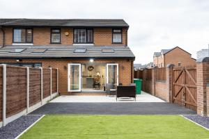 a brick house with a patio and grass at Spacious & Modern 4-Bedroom Townhouse in Manchester