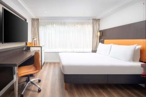 um quarto de hotel com uma cama, uma secretária e uma televisão em DoubleTree by Hilton London - Hyde Park em Londres