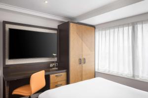 - une chambre avec un lit, une télévision et une chaise dans l'établissement DoubleTree by Hilton London - Hyde Park, à Londres