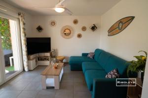 ein Wohnzimmer mit einem blauen Sofa und einem TV in der Unterkunft T2 climatisé avec WIFI et piscine in Vias