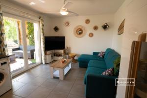 ein Wohnzimmer mit einem blauen Sofa und einem TV in der Unterkunft T2 climatisé avec WIFI et piscine in Vias