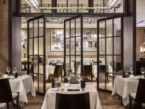 een restaurant met witte tafels, stoelen en ramen bij Fairmont Quasar Istanbul Hotel in Istanbul