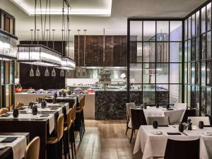 restauracja z białymi stołami i krzesłami oraz kuchnią w obiekcie Fairmont Quasar Istanbul Hotel w Stambule