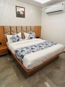 - une chambre dotée d'un grand lit avec des oreillers bleus et blancs dans l'établissement Hotel M Grand, à Ahmedabad