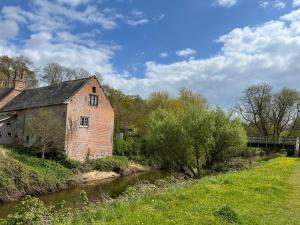 an old brick building next to a river at Otter Holt, beautiful East Devon in Tipton Saint John