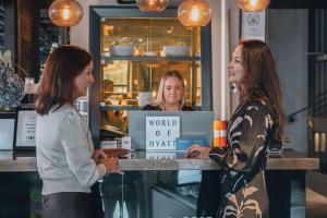 zwei Frauen stehen an einem Tresen mit einem Schild in der Unterkunft Story Hotel Signalfabriken, part of JdV by Hyatt in Sundbyberg