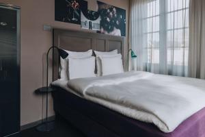 a bedroom with a large bed with white sheets and pillows at Story Hotel Signalfabriken, part of JdV by Hyatt in Sundbyberg