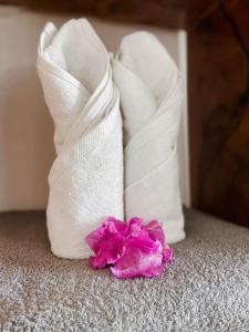 two white towels and a pink flower on the floor at Zanzibar Gem Beach Bungalows in Bwejuu