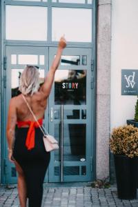 Una donna che cammina davanti a un palazzo con il braccio in aria di Story Hotel Signalfabriken, part of JdV by Hyatt a Sundbyberg
