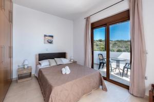 a bedroom with a bed and a balcony with a table at Villa Kiotari by Villa Plus in Kiotari