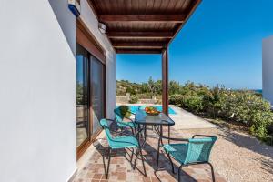 un patio con sillas y una mesa con vistas al océano en Villa Kiotari by Villa Plus, en Kiotari
