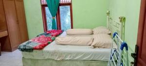 a bed in a room next to a window at Buhit Guest House Samosir in Pangururan