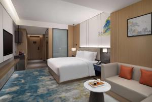 una camera d'albergo con letto e divano di Ramada Encore by Wyndham Dongguan Chang an a Dongguan