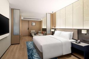 una camera d'albergo con un grande letto e una TV di Ramada Encore by Wyndham Dongguan Chang an a Dongguan