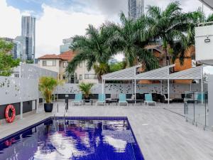 a pool on the roof of a building with palm trees at Mercure Brisbane Spring Hill in Brisbane
