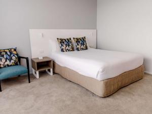 a bedroom with a large bed and a chair at Mercure Brisbane Spring Hill in Brisbane