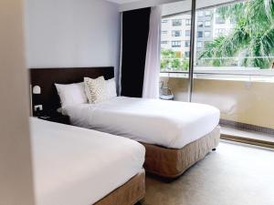 two beds in a hotel room with a window at Mercure Brisbane Spring Hill in Brisbane