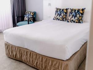 Cama en habitación con una gran sábana blanca en Mercure Brisbane Spring Hill en Brisbane