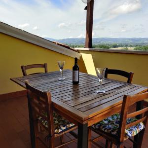 - une table en bois avec une bouteille de vin et 2 verres dans l'établissement attico umbria, à Collepepe