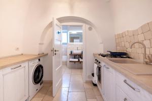 a kitchen with a sink and a washer and dryer at Trullo degli Anelli in Masseria in Cisternino