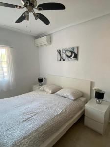 een witte slaapkamer met een bed en een plafondventilator bij Ground floor apartment Torrevieja Spain in Orihuela