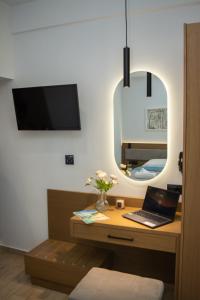 a bedroom with a desk with a laptop and a mirror at Hotel Golden Sun in Néa Meságkala