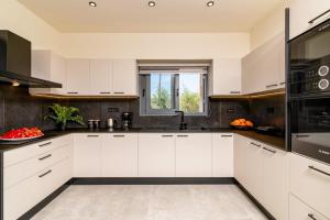 a kitchen with white cabinets and a window at Villa Casa Liveris by Villa Plus in Akrotiri