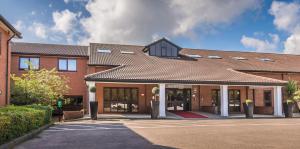 a large brick building with a roof at Best Western Rockingham Forest Hotel in Corby