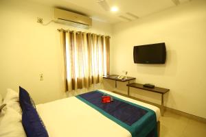 um quarto de hotel com uma cama e uma televisão em OYO NIMALAN RESIDENCY em Chennai