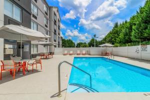 a swimming pool with tables and chairs and an umbrella at Holiday Inn Spartanburg Northwest in Spartanburg