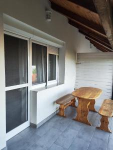 een houten tafel en bank in een kamer met ramen bij Éva Apartmanház 3 in Csopak