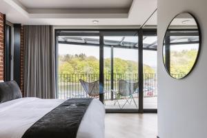1 dormitorio con cama, espejo y balcón en The Cliffe at the Quay en Donegal