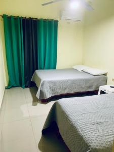 two beds in a room with green curtains at Hotel Vista Sur in Los Patos +8 photos