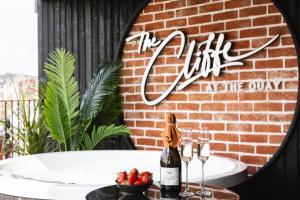 un tavolo con una bottiglia di vino e una ciotola di frutta di The Cliffe at the Quay a Donegal