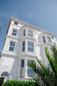 a white building with windows and a palm tree at Southsea, Portsmouth - Two Bedroom Apartment - Newly Refurbished Throughout - Treetop Sea Views in Portsmouth