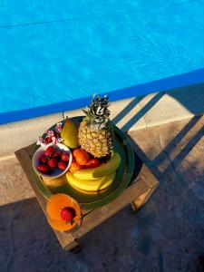 a plate of fruit on a table next to a pool at Olive Dream Thassos Luxury Villas in Skala Rachoniou