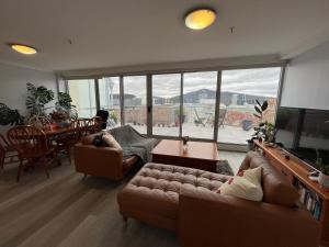 a living room with a couch and a table and a large window at Private room with ensuite in the CBD in Canberra