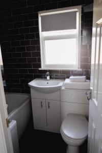 a bathroom with a toilet and a sink and a window at Family Chalets - 5 mins walk to beach, nr Great Yarmouth & Norfolk Broads in Scratby